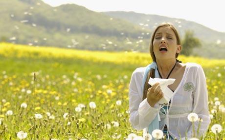 Woman sneezing with tissue in meadow